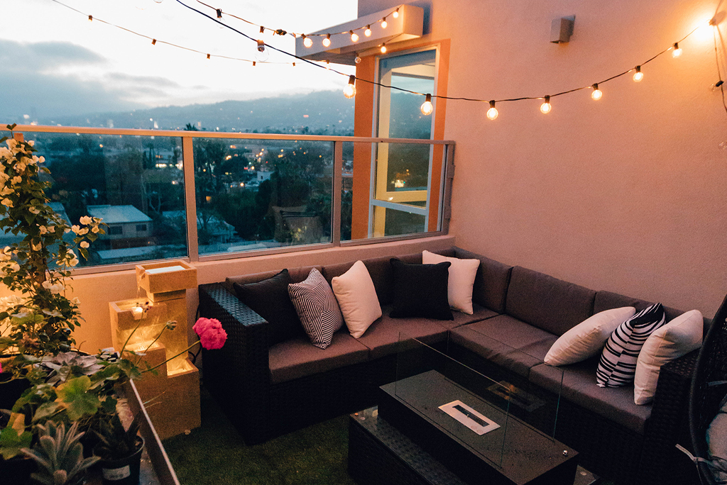 balcony at dusk with artificial grass, festoon lighting and rattan seating