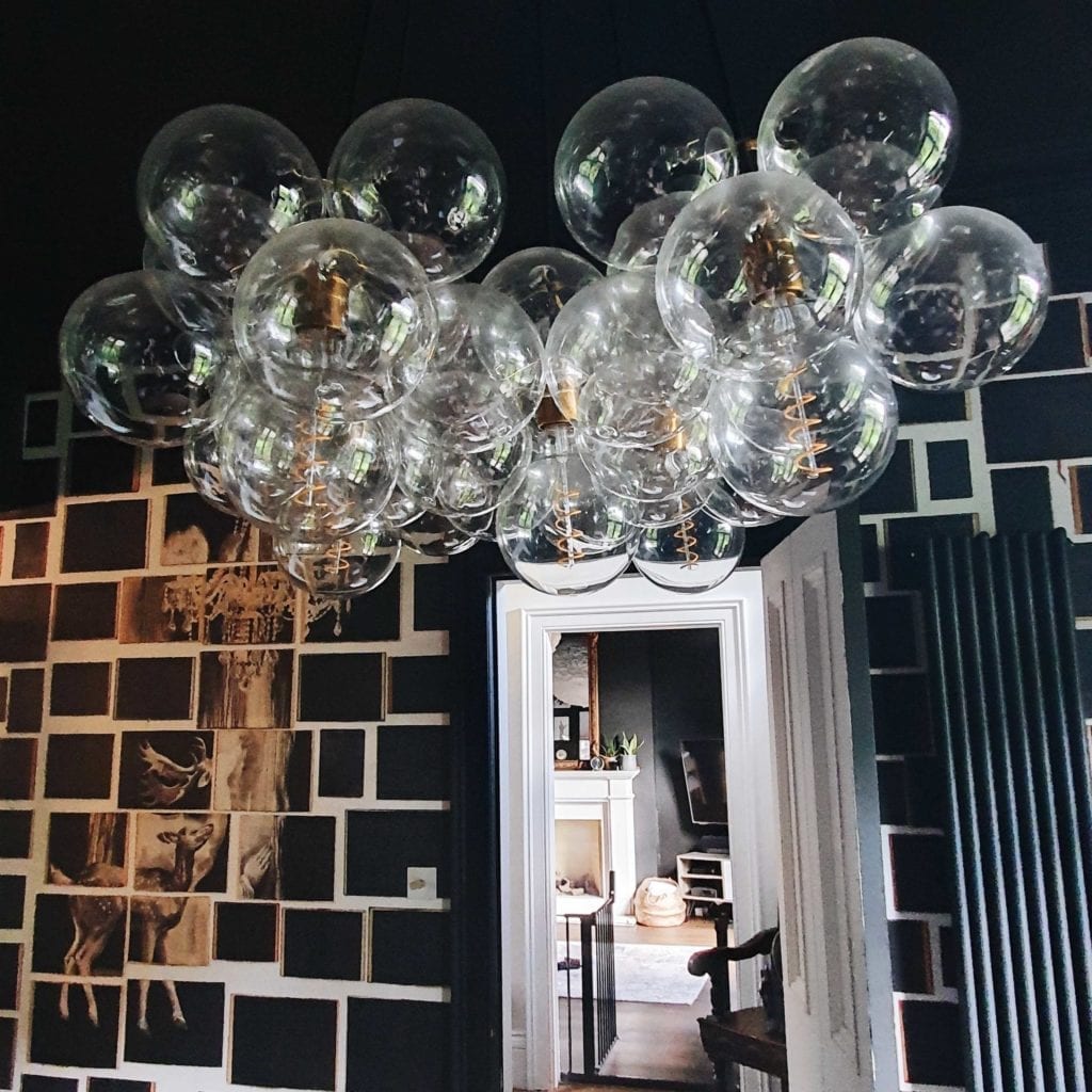 large clear bubble chandelier in black and white wallpapered living room