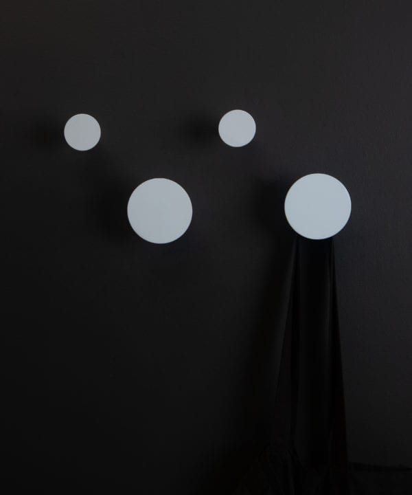 two large and two small light blue wall mounted coat hooks on a black wall