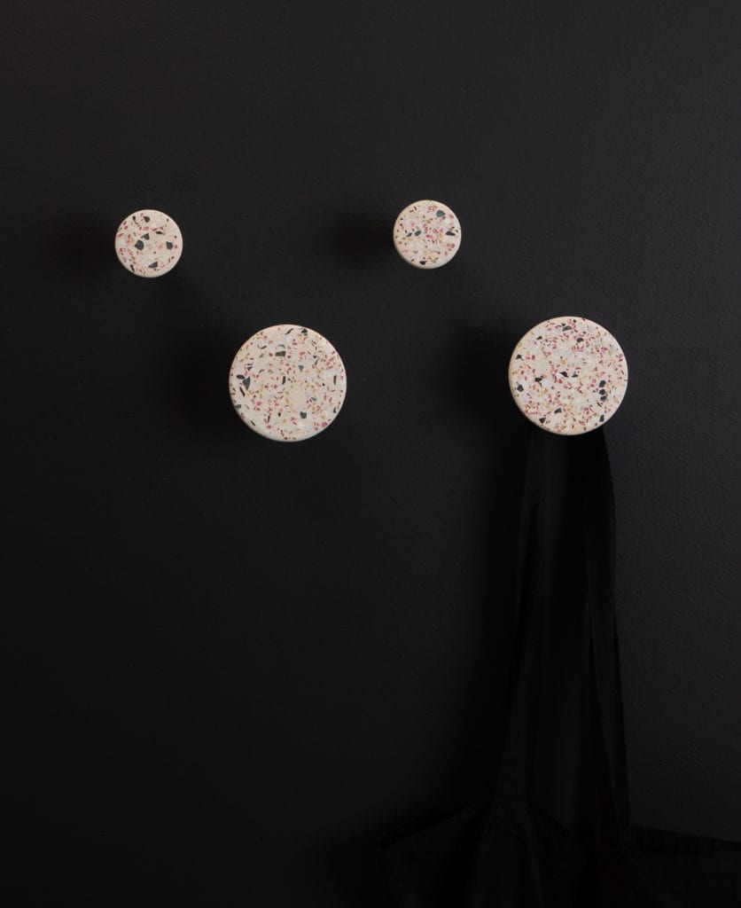 four white terrazzo bloums wall hooks on a black wall