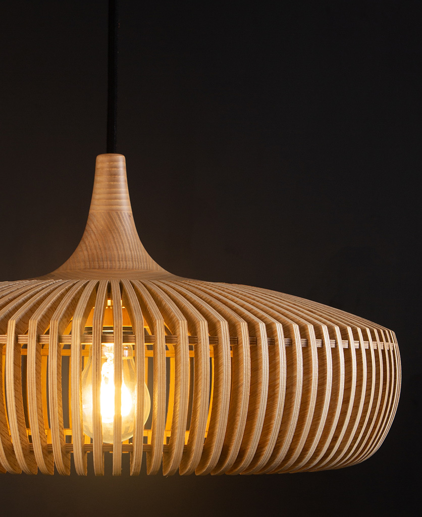 close up of umage clava dine wooden slatted pendant lampshade with black fabric cable against black background