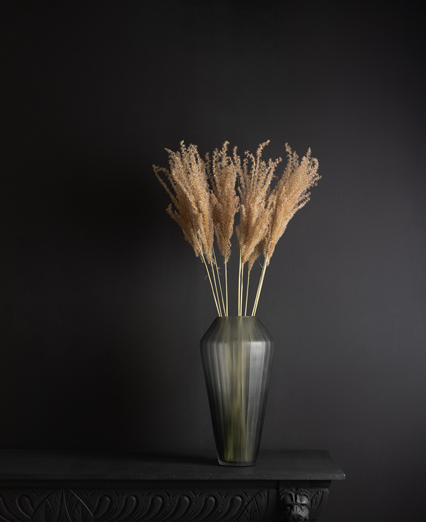 grey vase with fluffy reed grass bouquet against black background