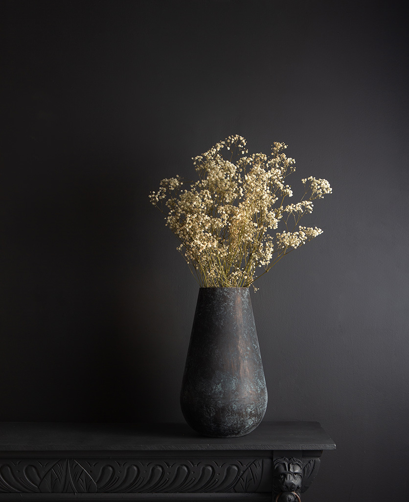 metal vase with preserved gypsophila bouquet against blck bckground