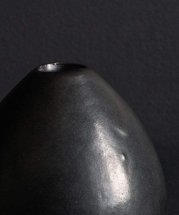 close up of black stem vase against black background