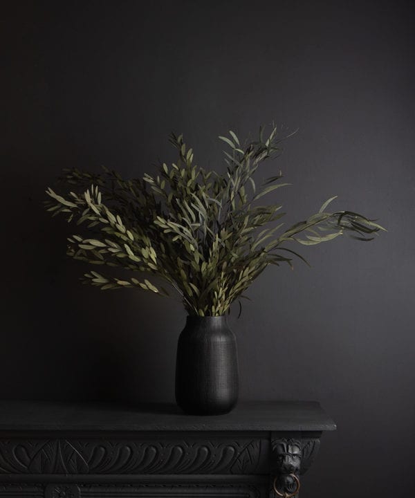 black vase with preserved green nicholii bouquet against black background