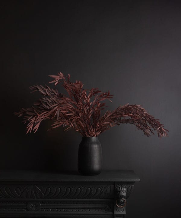 black vase with preserved red nicholii bouquet against black background