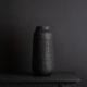 black tall vase against black background