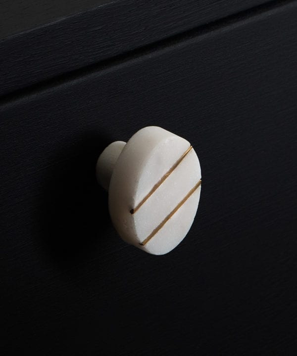 Barruzi white oval marble knob with two gold stripes on black drawer