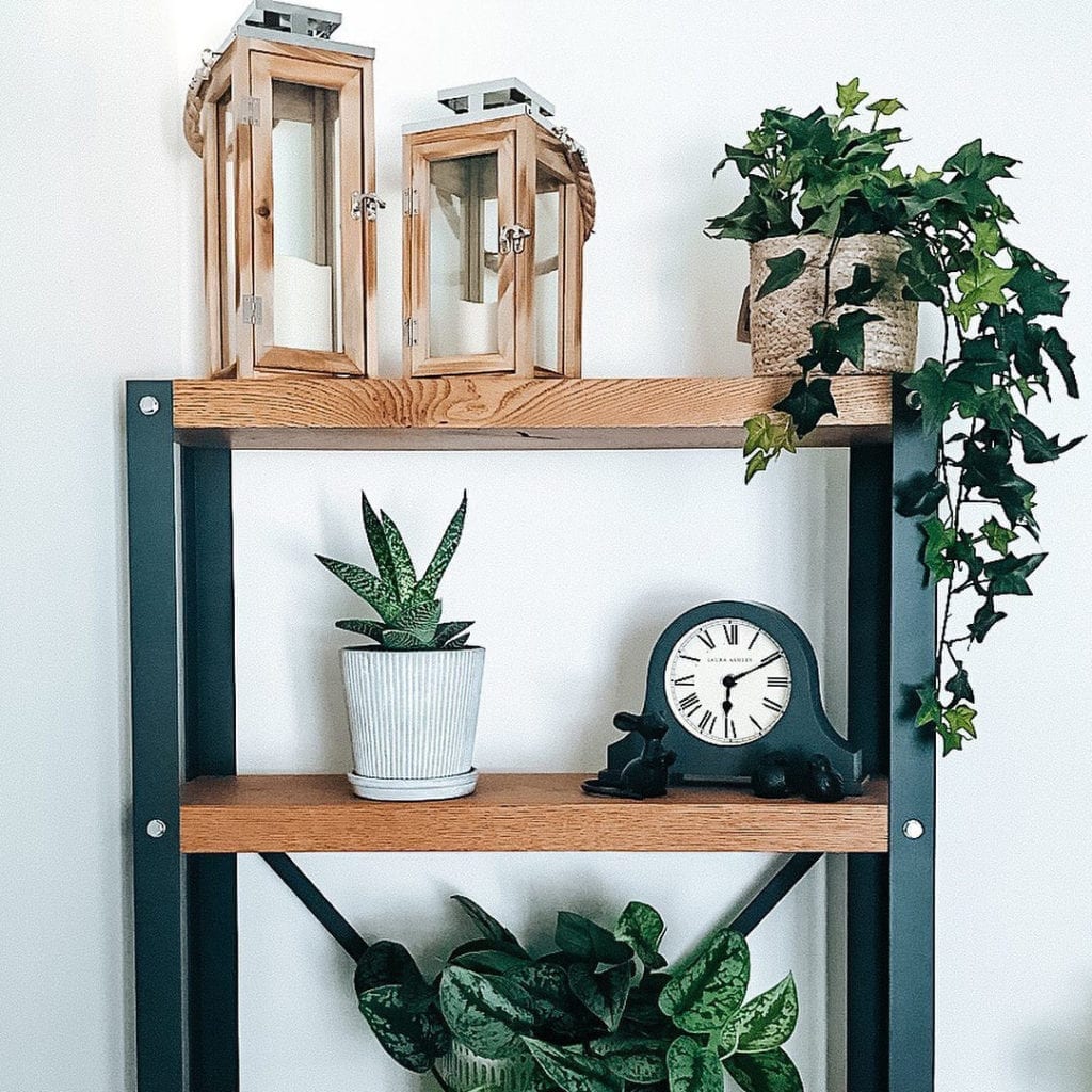 trailing ivy faux foliage in woven pot sitting on a shelving unit against a white wall