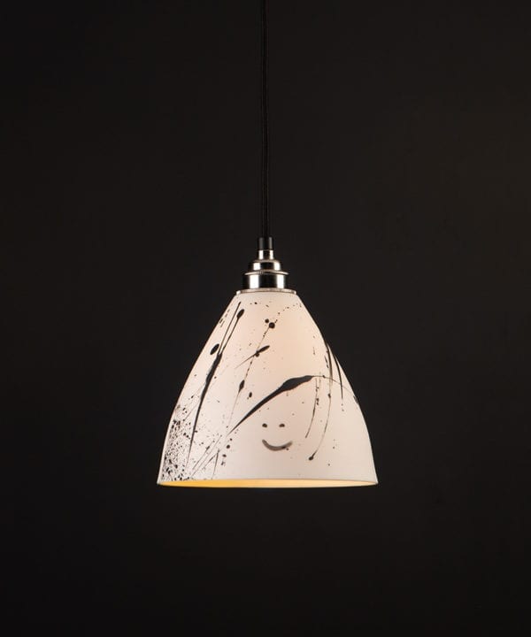 ceramic pendant light in white with black paint splatters on black background