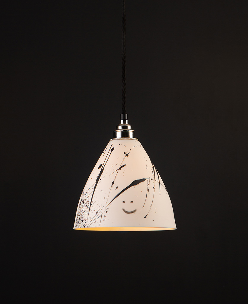 ceramic pendant light in white with black paint splatters on black background