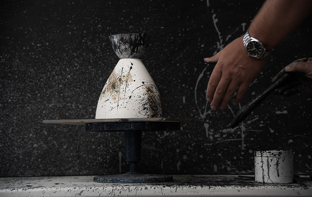 Michael flicking paint onto a white ceramic light shade