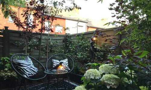 garden patio with two chairs and a table, a black raven table lamp and black monkey wall light