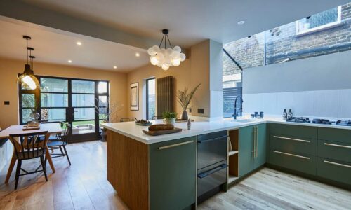 medium bubble chandelier suspended above island in a a green and white kitchen