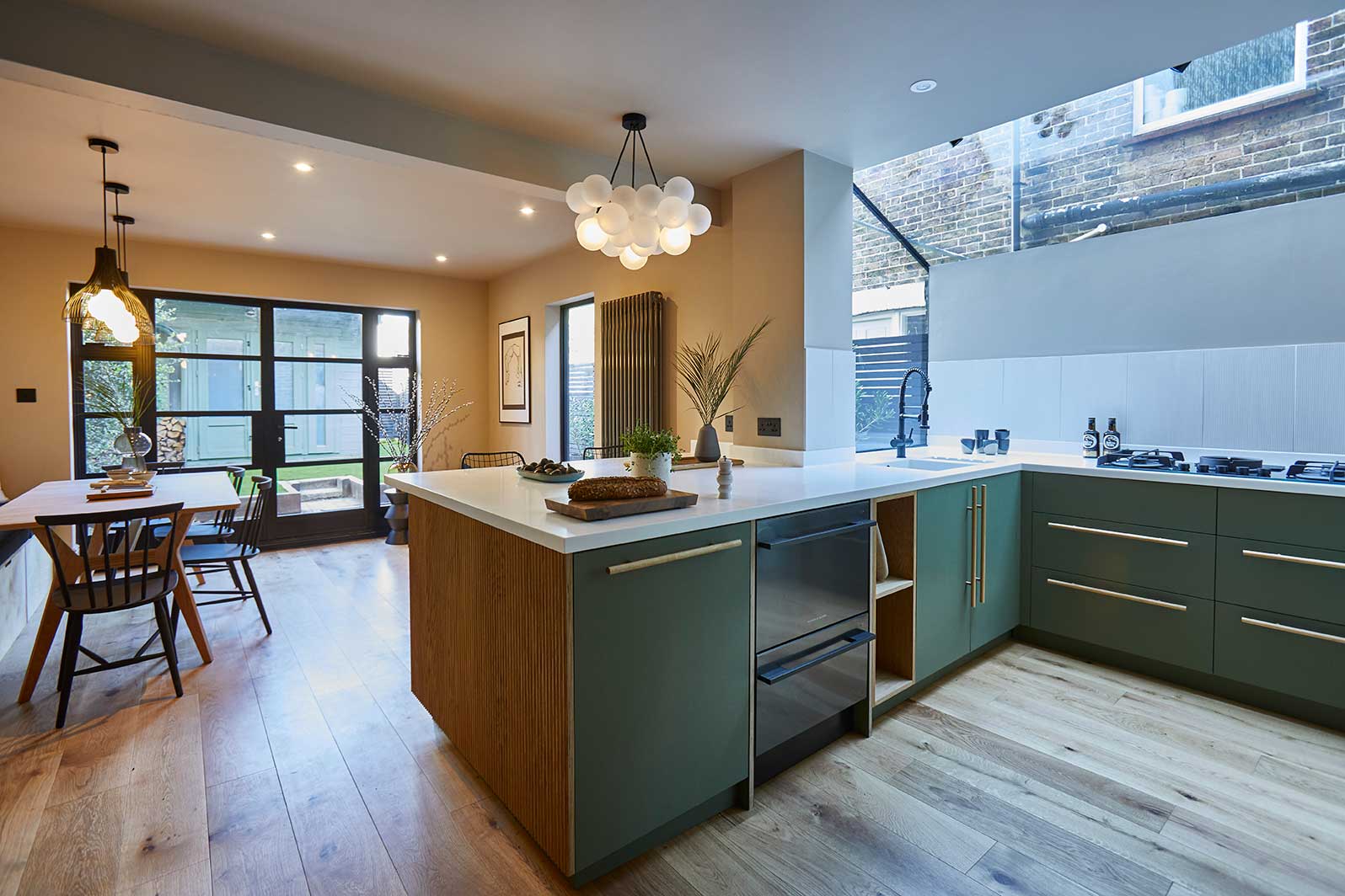 medium bubble chandelier suspended above island in a a green and white kitchen