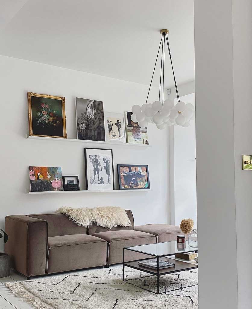 five point frosted bubble chandelier suspended in white living room alongside gallery wall with various works of art in frames