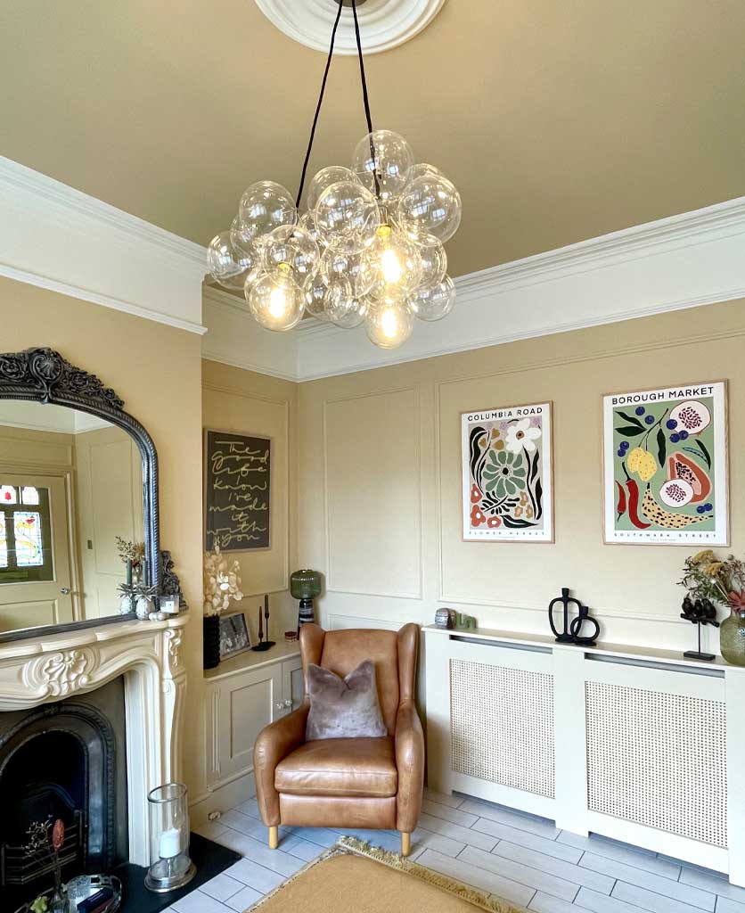 bubble pendant light suspended in light yellow victorian living room above a brown leather armchair