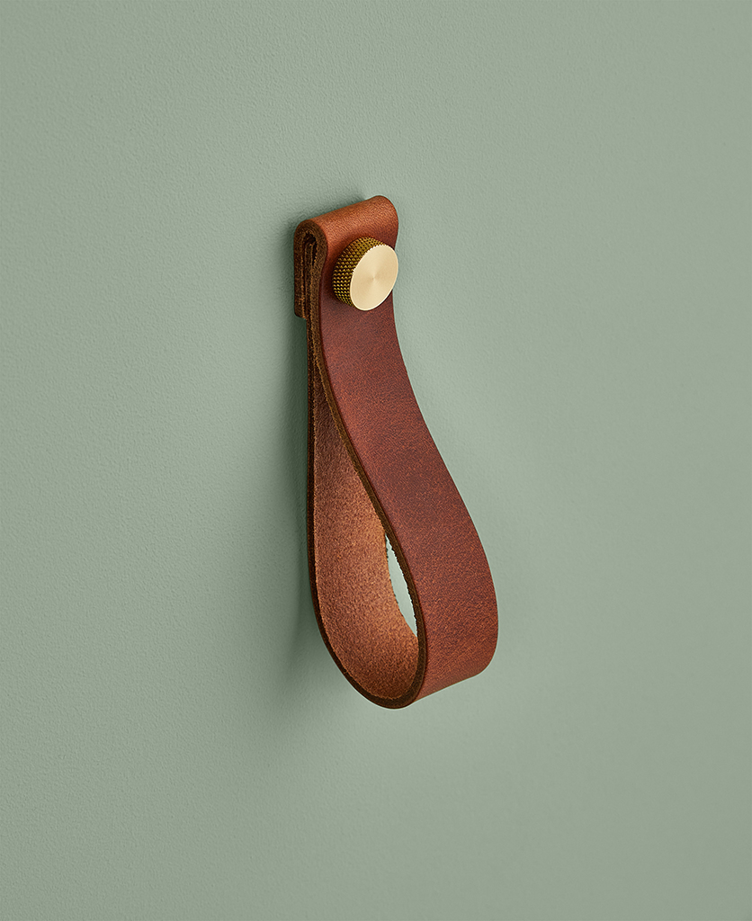 large dark tan magni handle with gold stud against sage green background