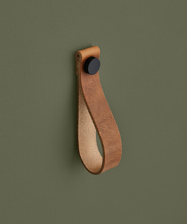 large light tan magni handle with black stud against dark green background