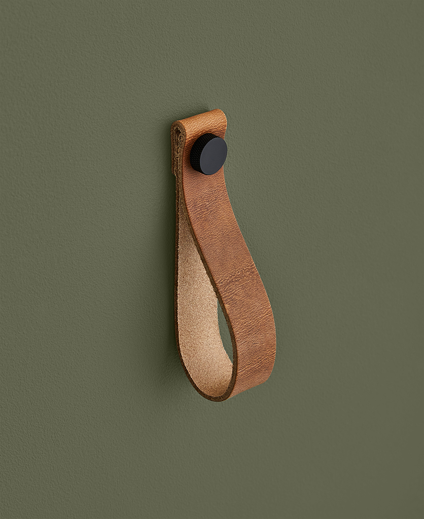 large light tan magni handle with black stud against dark green background