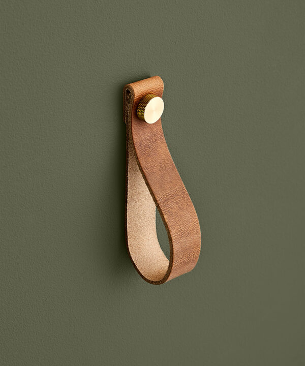 large light tan magni handle with gold stud against dark green background