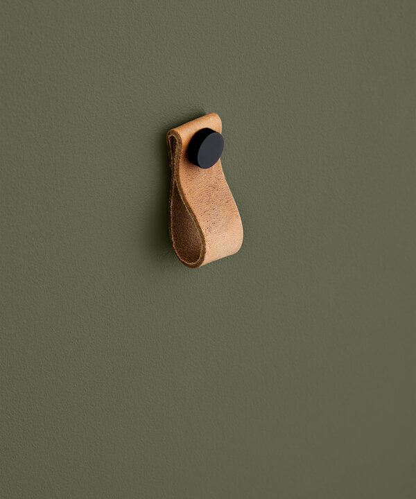 small light tan magni handle with black stud against dark green background