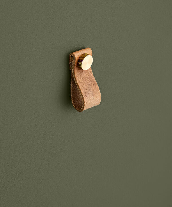 small light tan magni handle with gold stud against dark green background