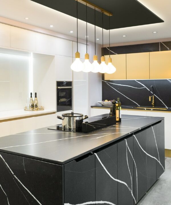 gold lanesborough multi-pendant light suspended above an induction hob an a black and white marble kitchen island