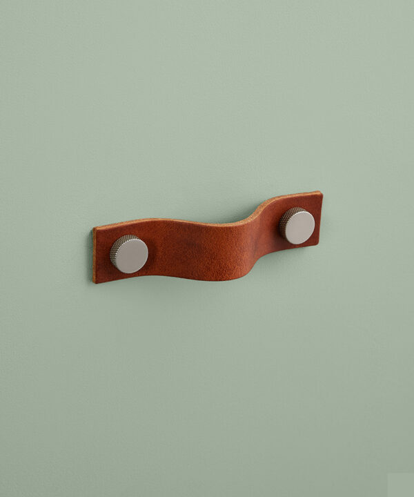 small dark tan Thor leather handle with silver knobs against green background