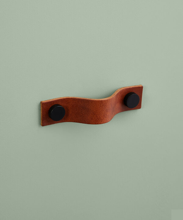 small dark tan Thor leather handle with black knobs against green background