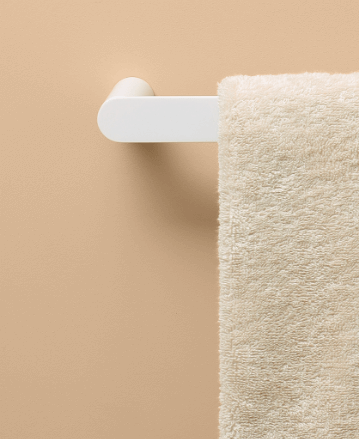 white hand towel rail with off-white towel against sandy background