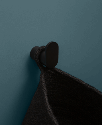 black robe hook holding a black dressing gown against a teal wall