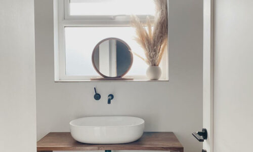 black wall mounted tap on an off-white wall in a bthroom