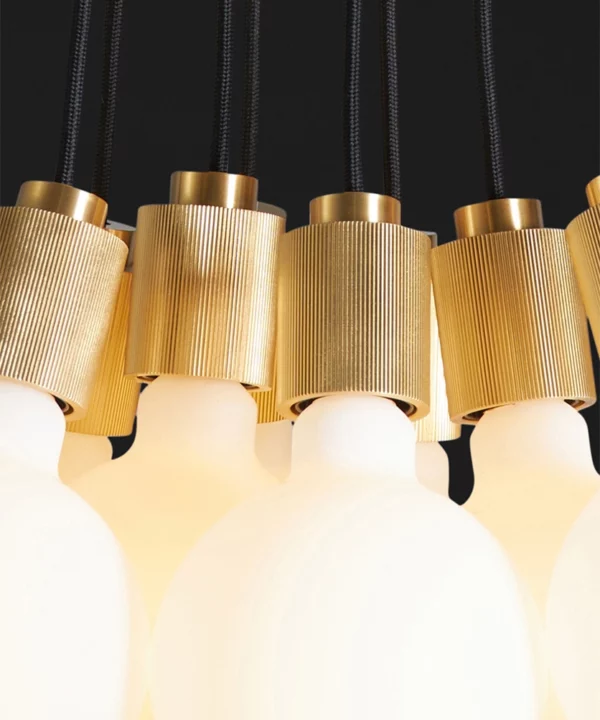 closeup of gold athenee statement pendant light against black background