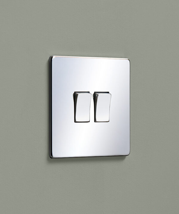 polished chrome mirrored double rocker light switch mounted on a dusty sage painted wall