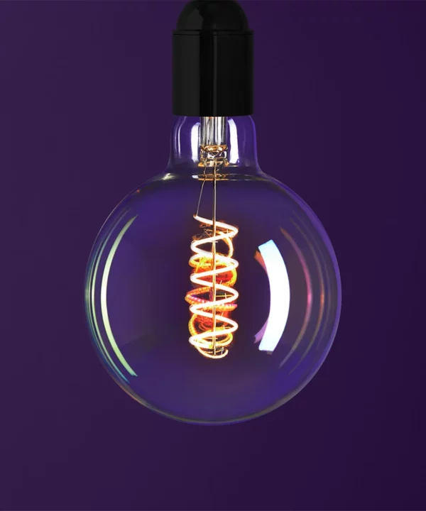 globe iridescent light bulb with spiral filament against purple background