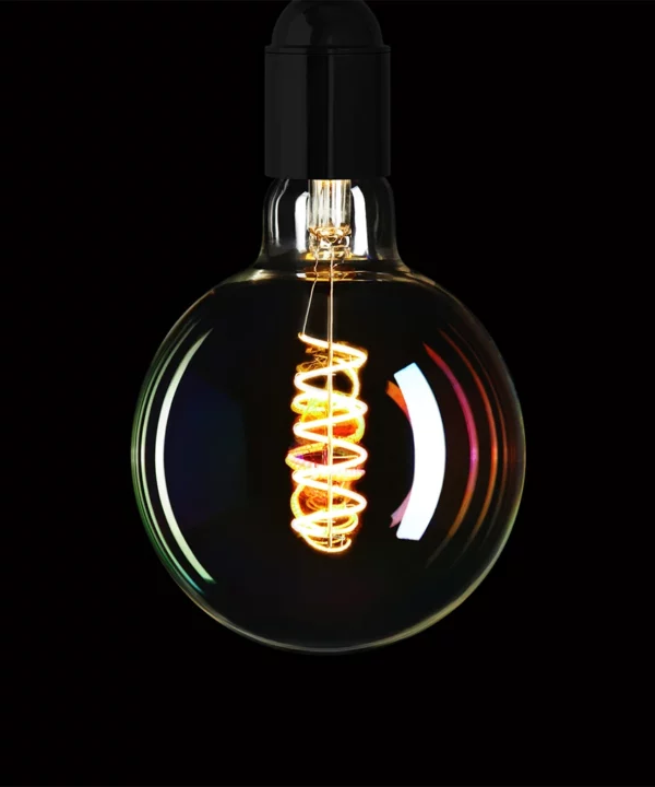 globe iridescent light bulb with spiral filament against black background