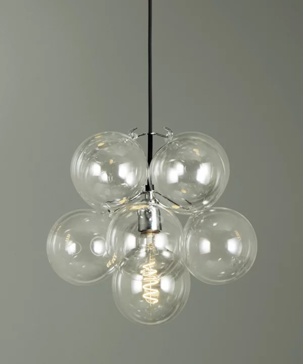 closeup of of small clear glass bubble pendant light with eight glass orbs against green background