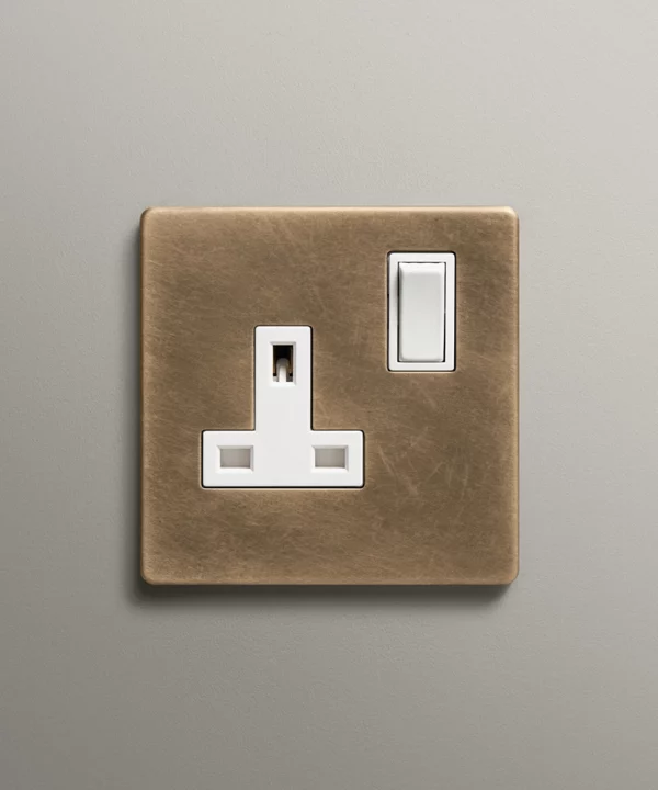 antique brass single plug socket on a neutral wall