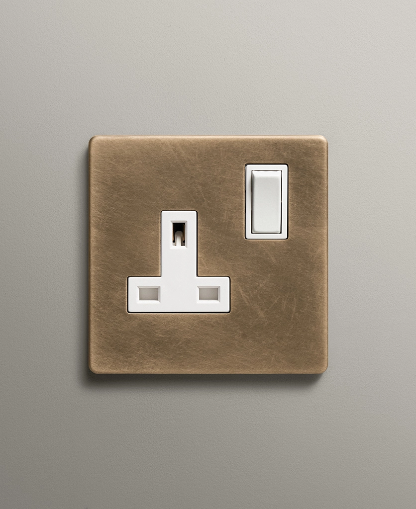 antique brass single plug socket on a neutral wall