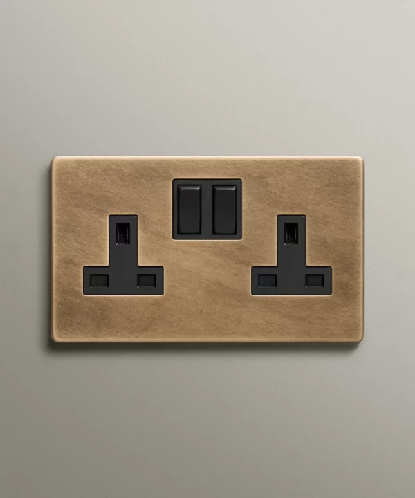 antique brass double socket with black inserts on a neutral warm grey background