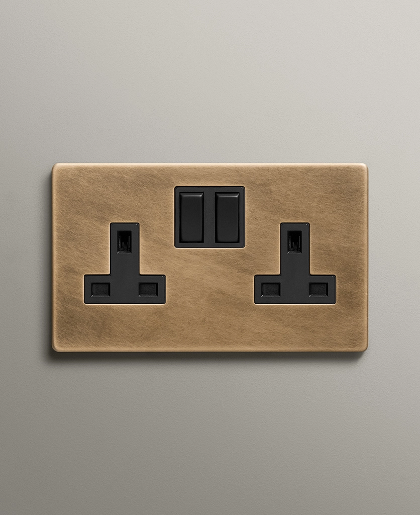 antique brass double socket with black inserts on a neutral warm grey background