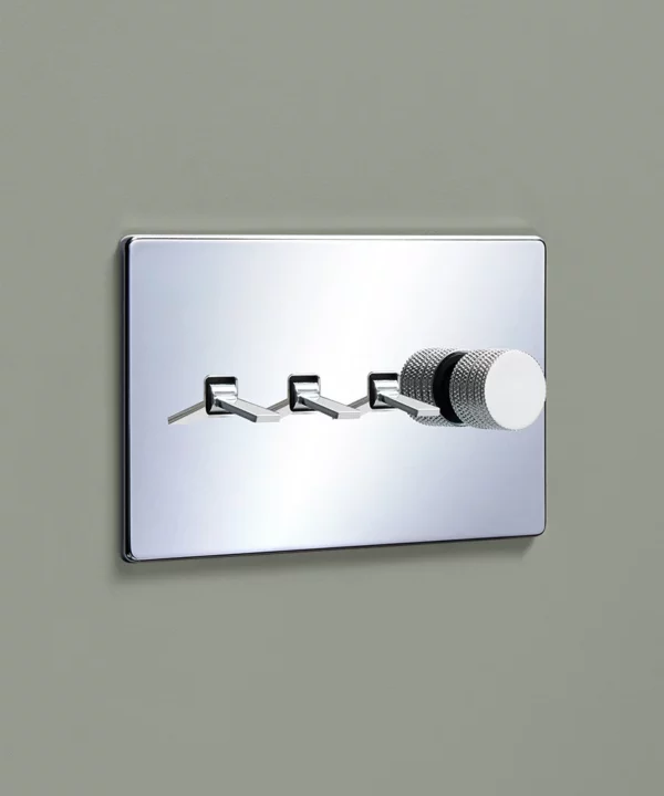 polished chrome 4g quadruple light switch with a combination of three tapered toggles and a knurled dimmer knob on a pale sage green painted wall