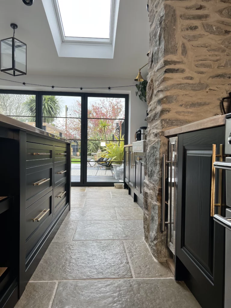 Gold Skyscraper handles against black kitchen cabinets.