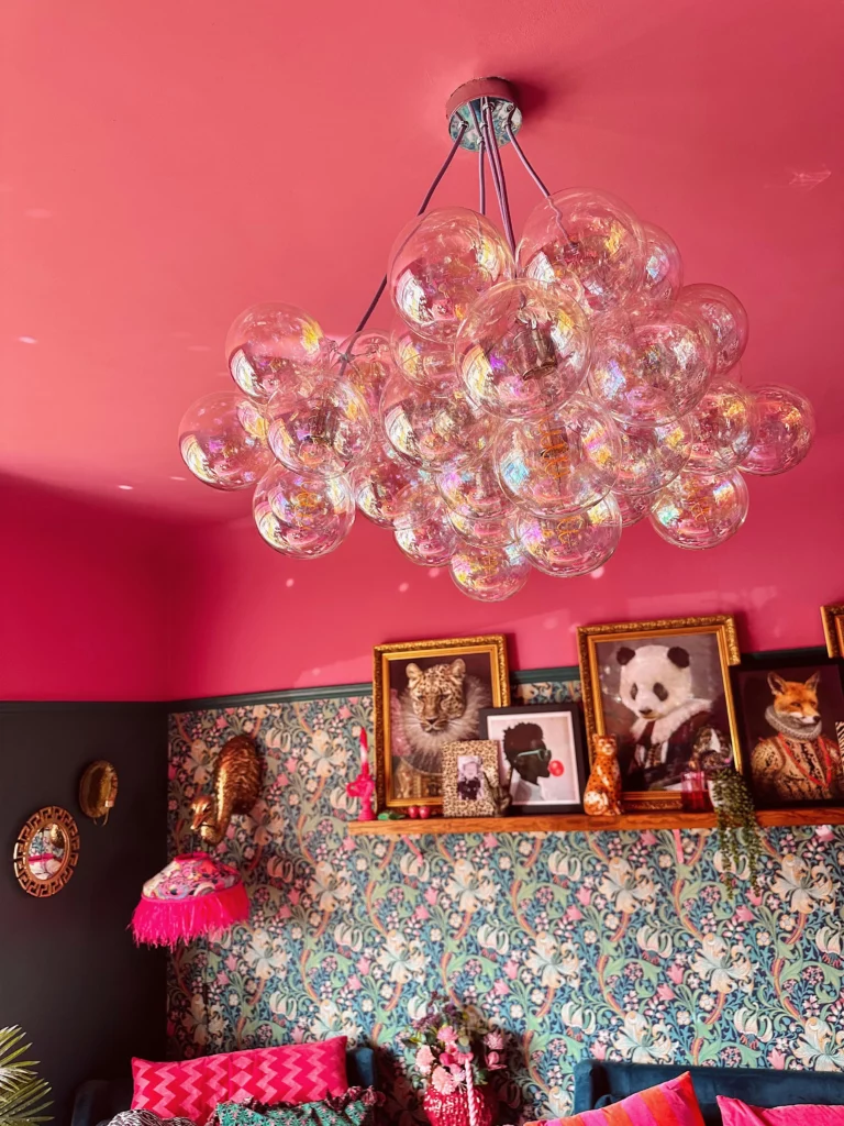 A close up of an iridescent bubble chandelier against a deep pink ceiling. 