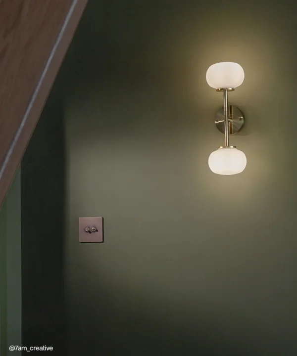 Gold Waldorf 2 Bulb Wall Light against a wall painted in forest green.