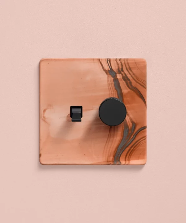 combination switch with one toggle and one dimmer - copper coloured on a pale pink painted wall