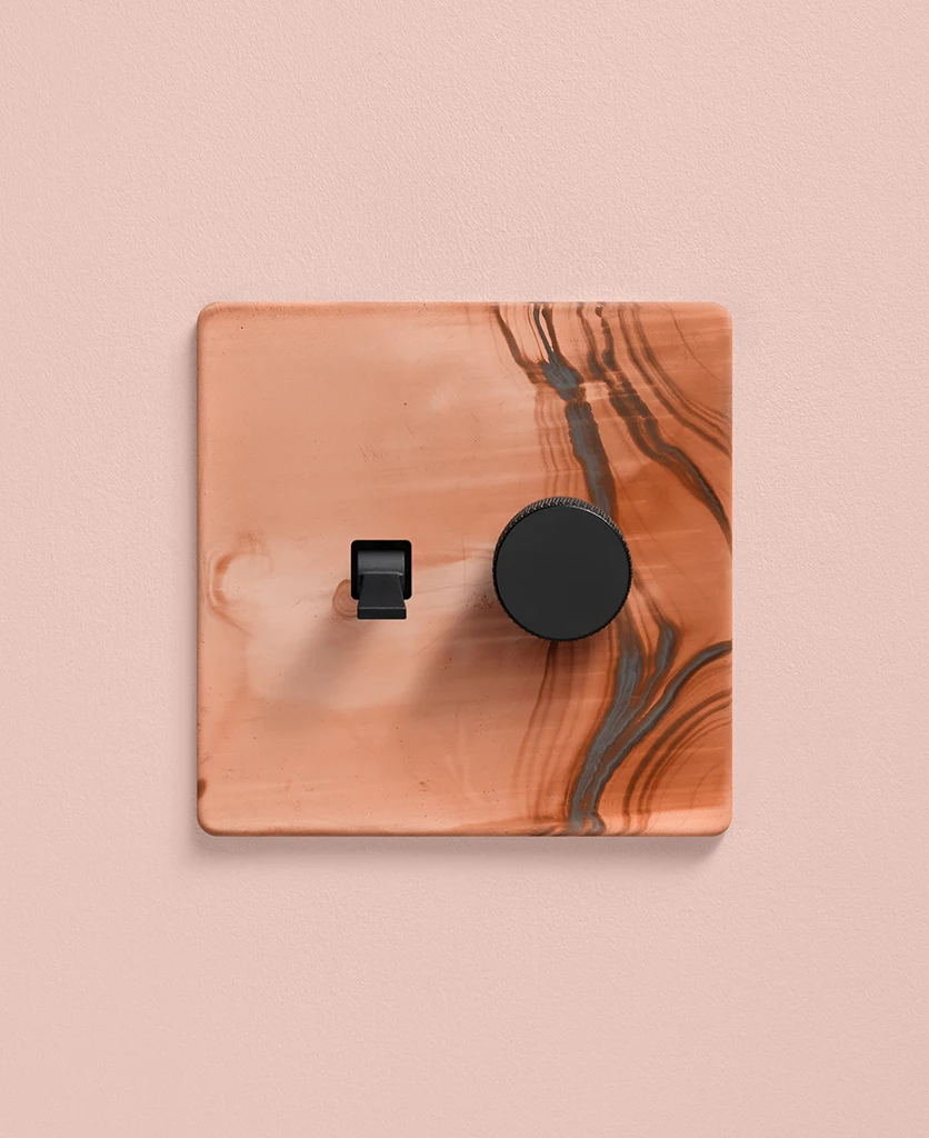 combination switch with one toggle and one dimmer - copper coloured on a pale pink painted wall