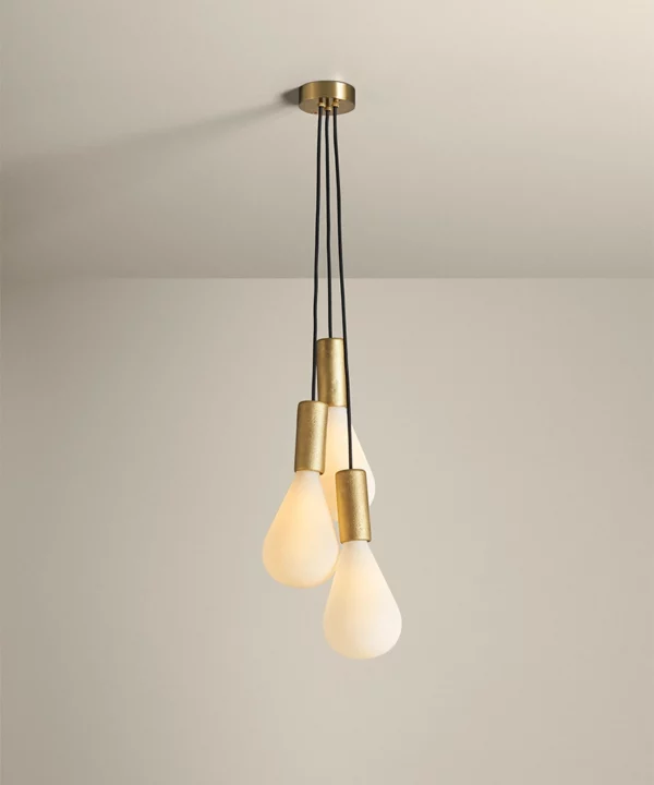 gold pendant light with three bulbs in a cluster on a neutral background