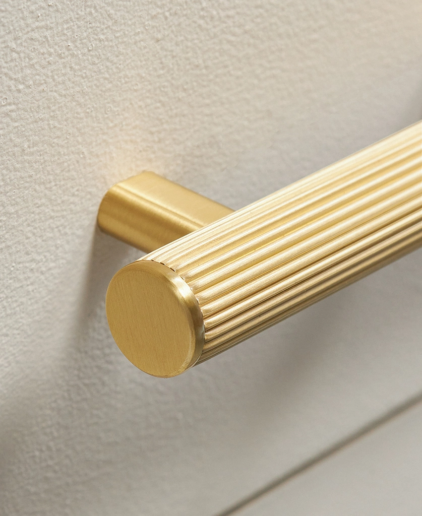gold ribbed chunky handle on a cream modern kitchen unit